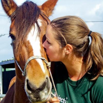 Female Equine Therapy intern kisses a horse at a centre during a therapy placement in South Africa. Projects Abroad Equine Therapy intern in South Africa kisses a horse outside a therapy placement.